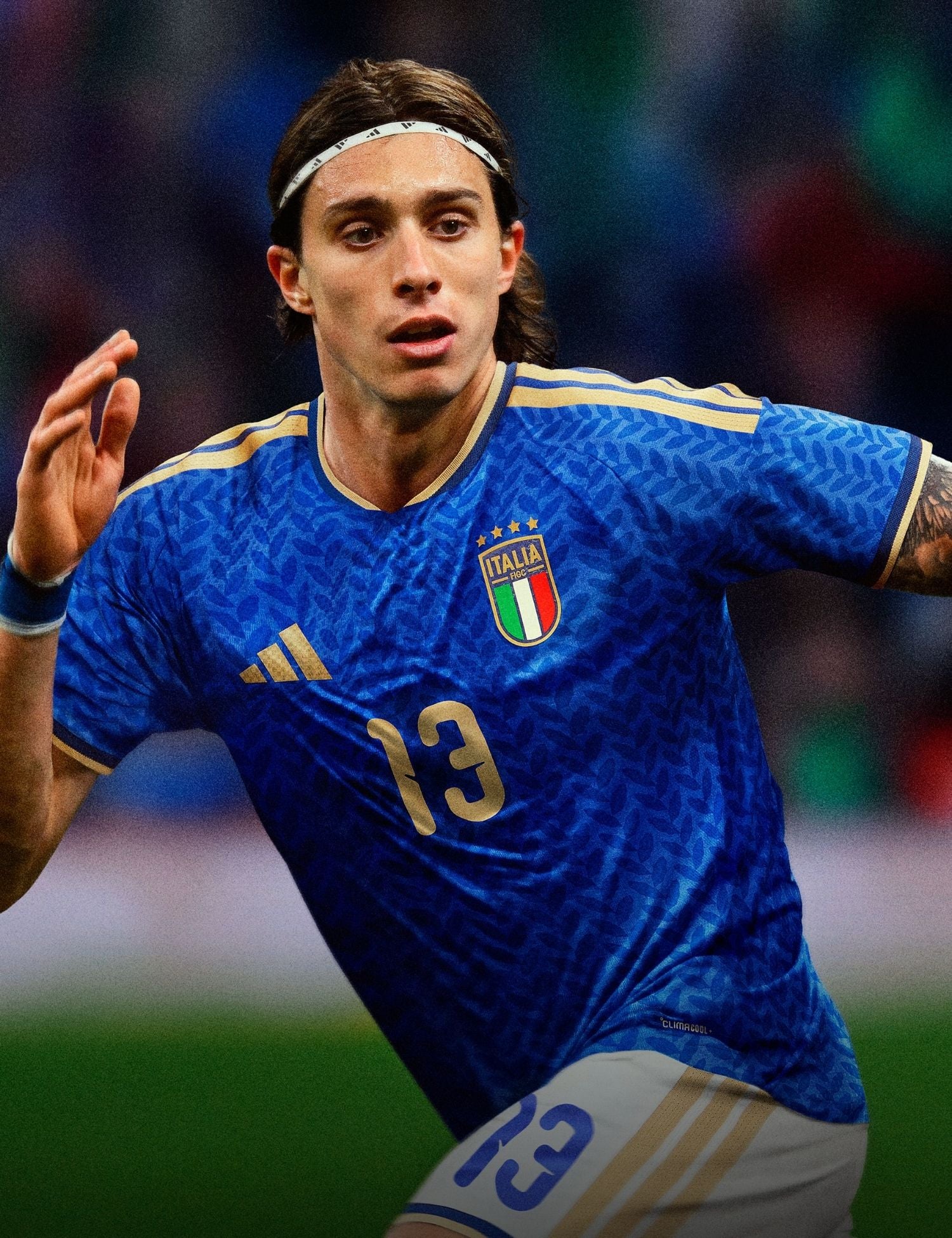 Soccer player in a blue jersey with Italian flag emblem on a blurred stadium background