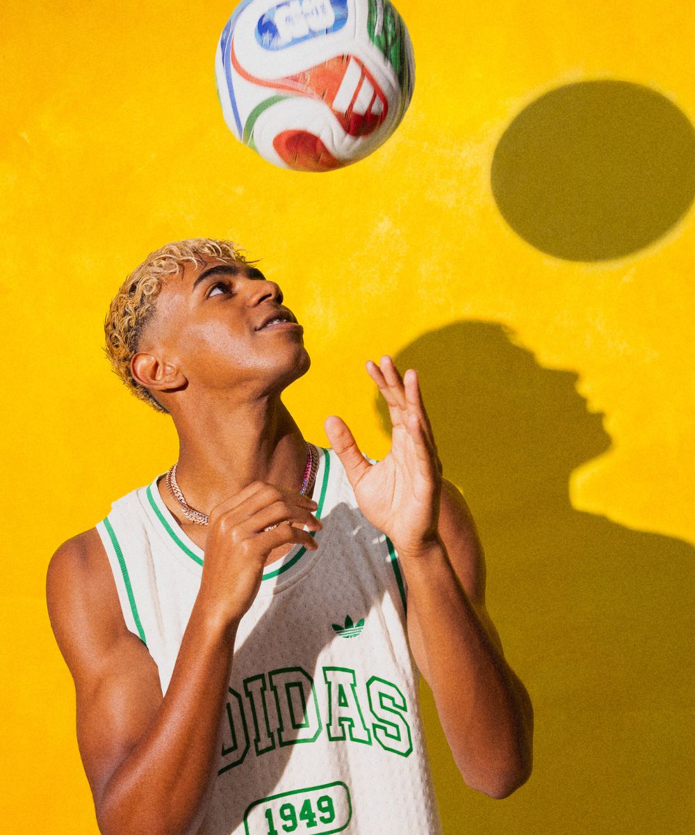 Lamine Yamal in adidas jersey playing with a colorful Trionda ball against a yellow background