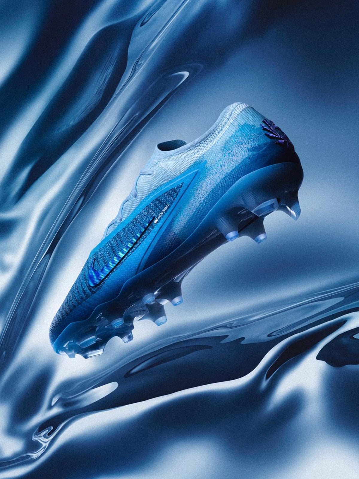 Blue Nike Phantom 6 Erling Haaland Player Edition soccer cleat displayed against flowing metallic blue fabric.